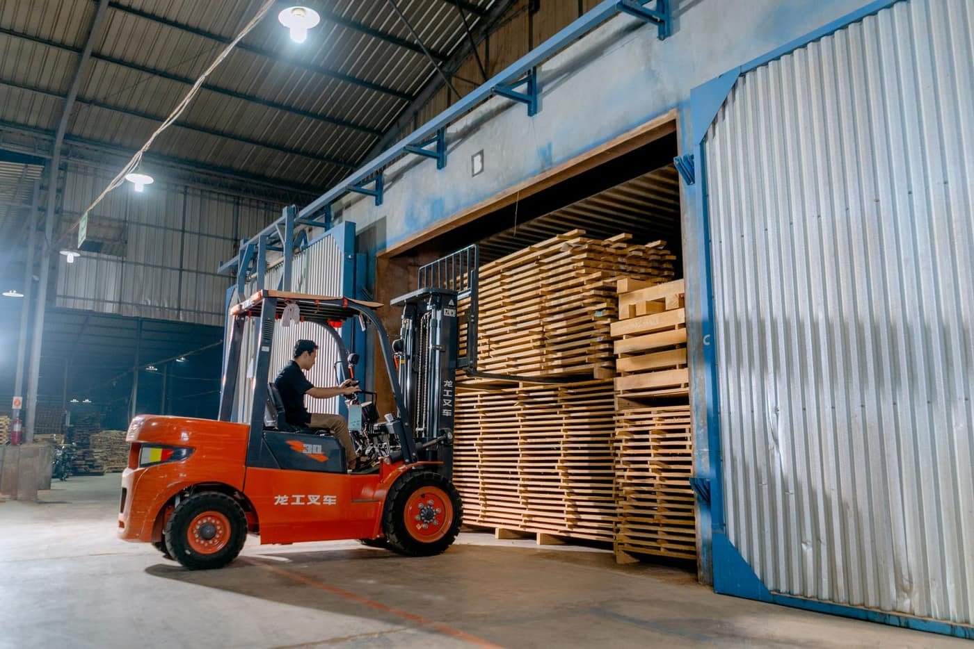 A forklift loading wooden pallets in a warehouse